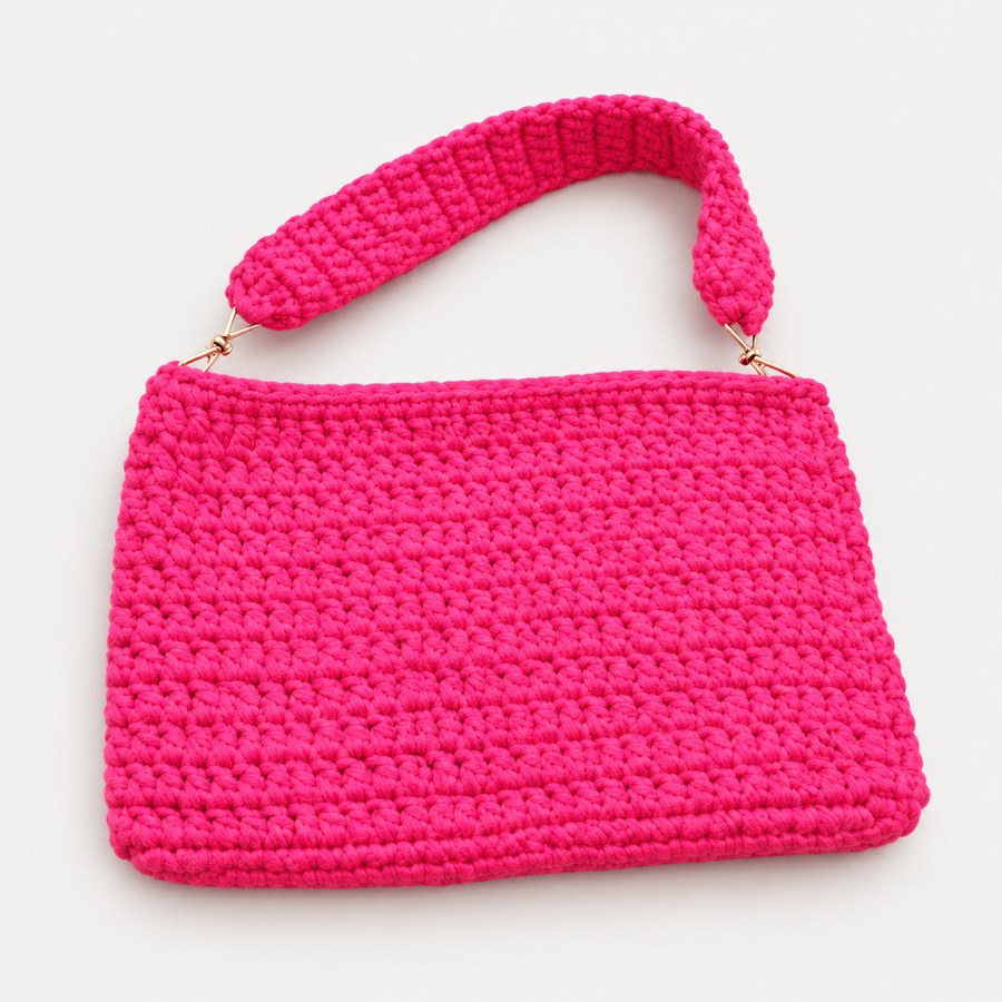 Cartera fucsia de Qipuc Threads sobre fondo claro de estudio